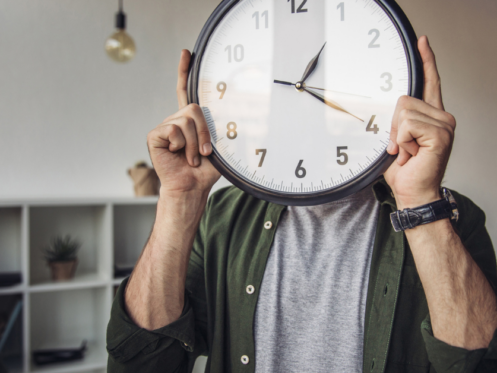 image of man hold clock in front of his face