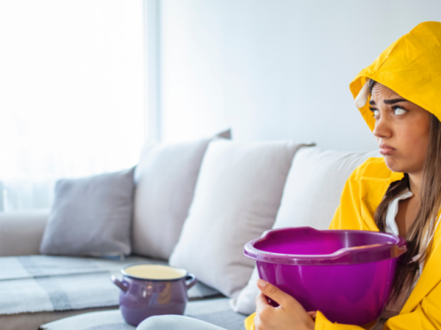 image of a female holding a bucket on a couch catching leaking water